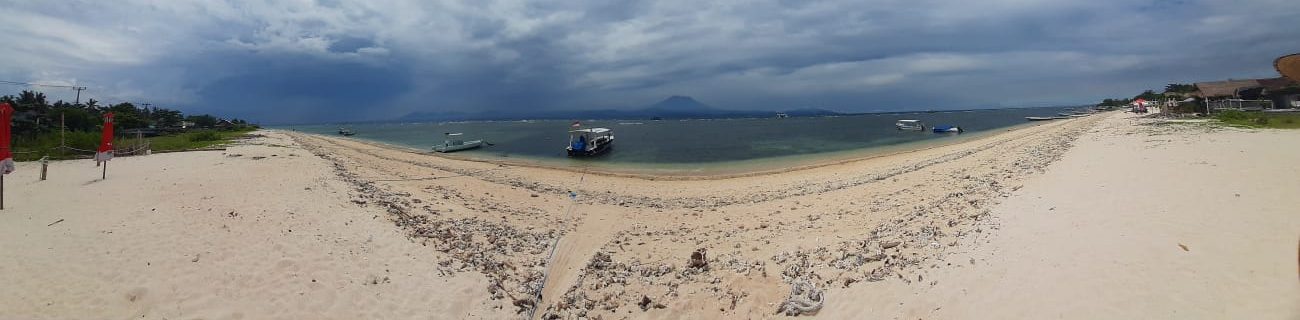 Wide shot of a beach on Nusa Lembongan with a volcano in the background.