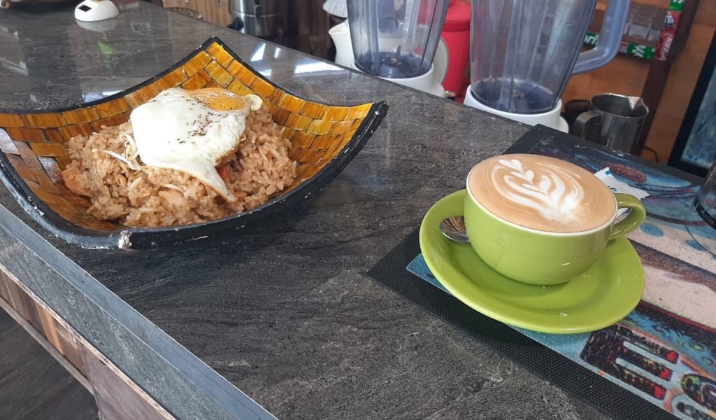 Fried rice with egg on top with cappuccino served at a bar.
